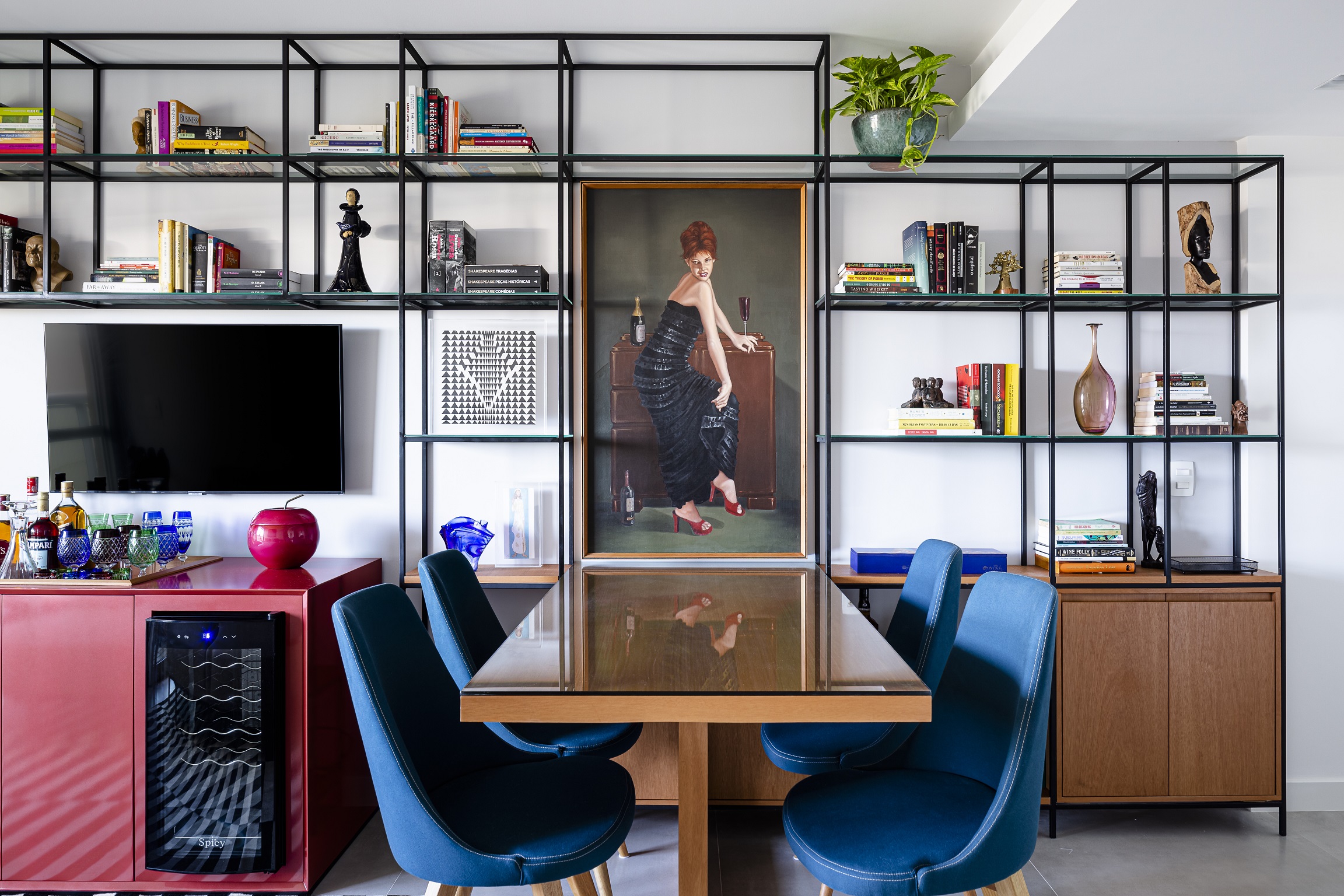 Loft de 45 m² ganha décor descolado baseado na coleção de arte do morador. Projeto de Vivian Reimers. Na foto, sala com quadro, estante de serralheria e tapete listrado.