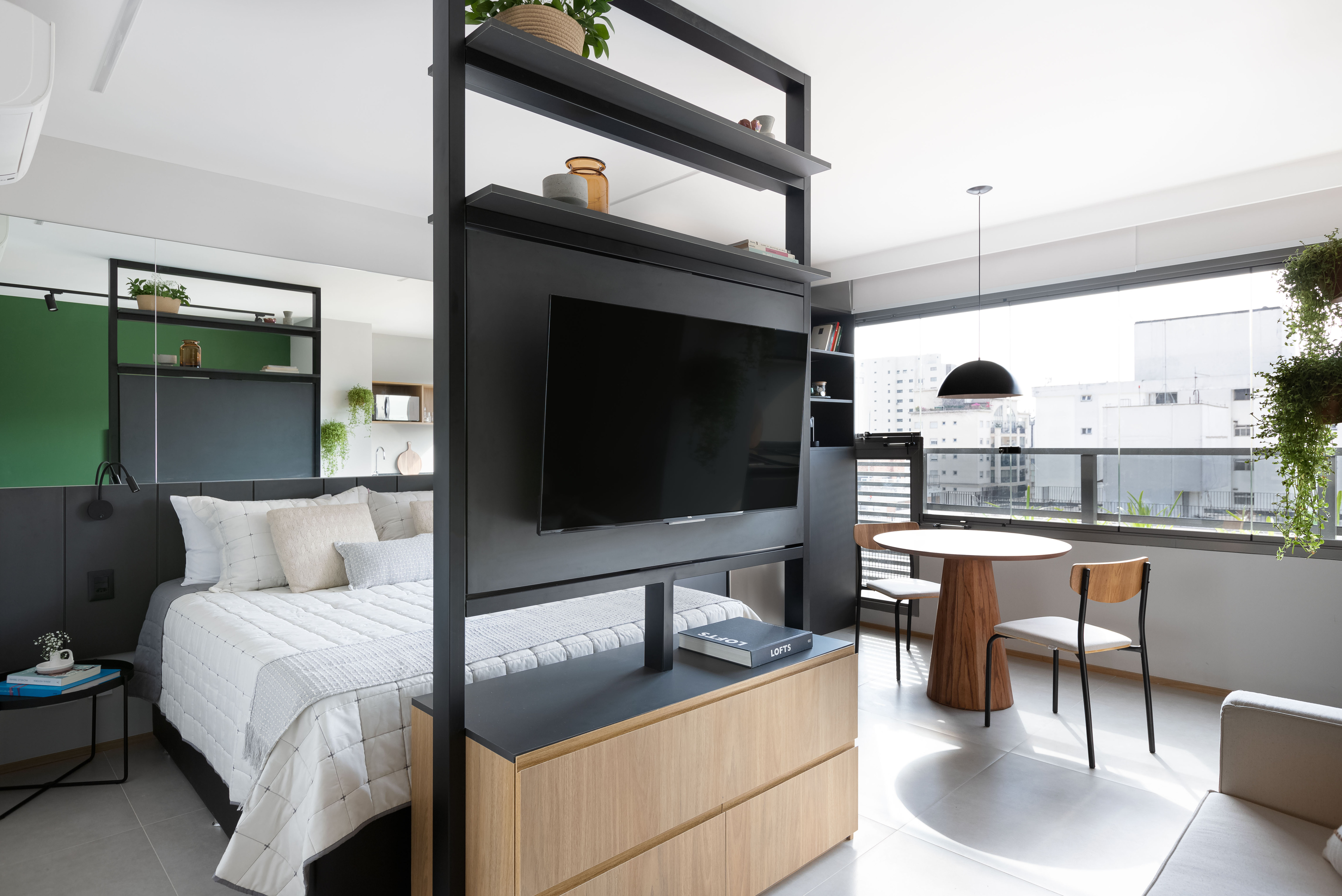 Apê de 25 m² ganha projeto jovem, integrado e funcional. Projeto de Carolina Gava, Na foto, quarto, varanda e estante com tv giratória.