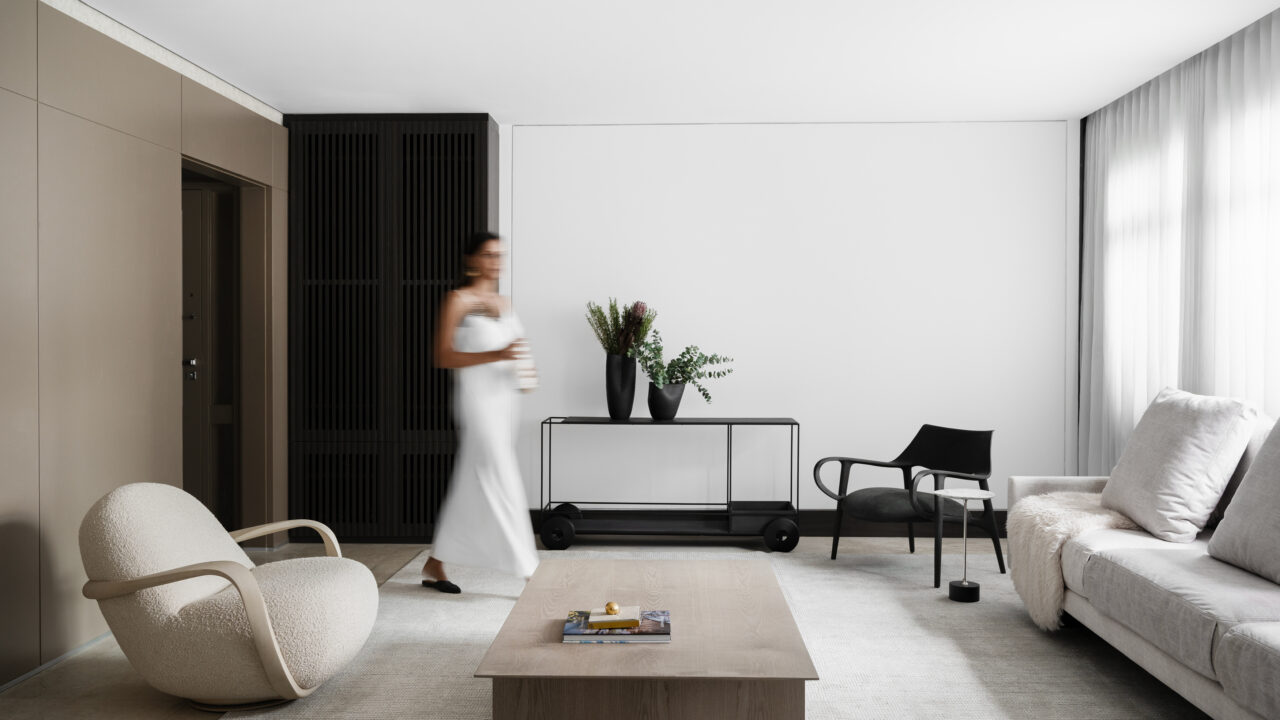 Bege, preto e branco protagonizam décor minimalista deste apê mineiro. Projeto de AW Arquitetura. Na foto, sala com sofá, poltrona, mesa e tapete.