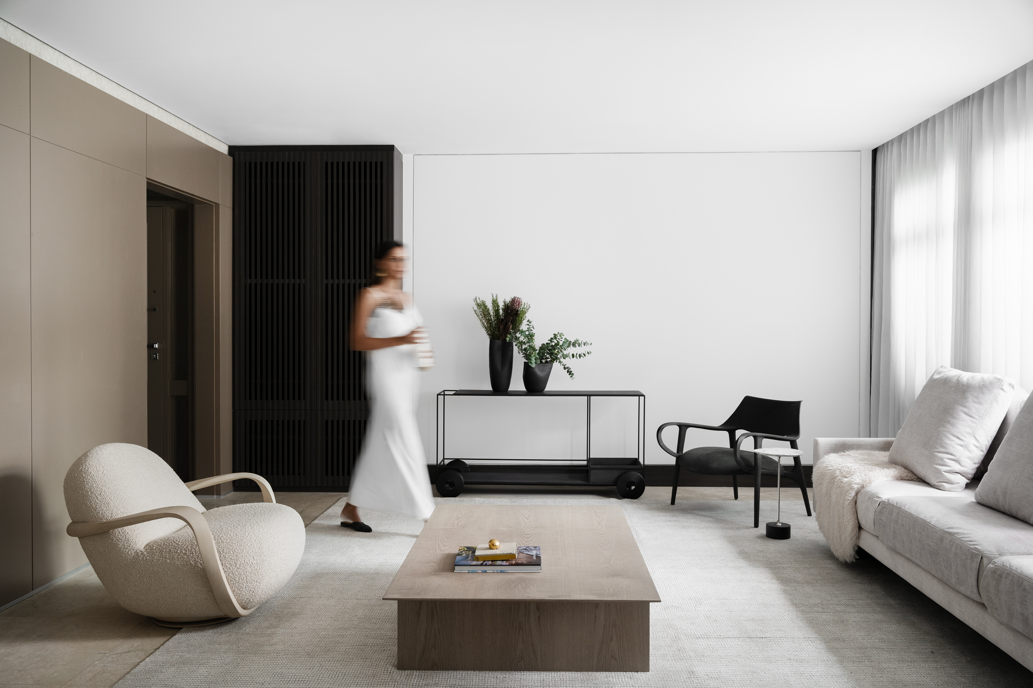 Bege, preto e branco protagonizam décor minimalista deste apê mineiro. Projeto de AW Arquitetura. Na foto, sala com sofá, poltrona, mesa e tapete.