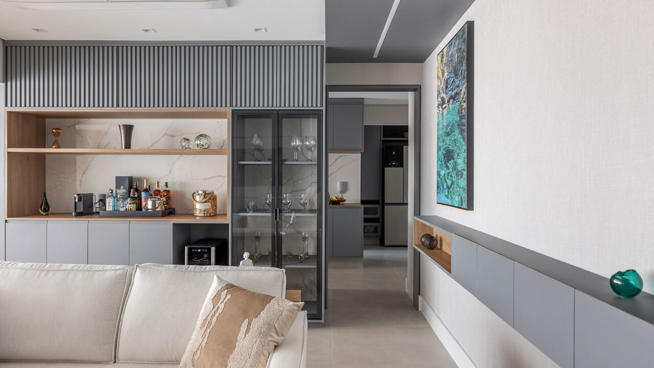 Blaia e Moura Arquitetos privilegia a integração neste apartamento em SP. Na foto, sala com cristaleira, armário ripado e sofá.