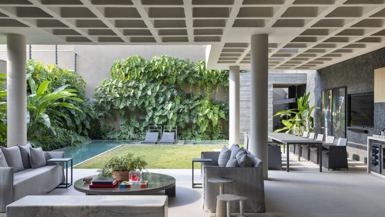 Casa de concreto armado ganha vida com vegetação e pontos de cor. Projeto de David Bastos. Na foto, varanda gourmet com teto de concreto.