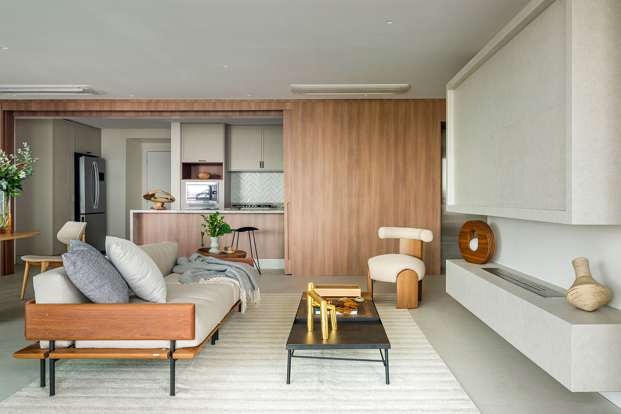 Apartamento de 197 m² feito para receber e curtir em família. Projeto de Mariana Leal, do Morada 31.12. Na foto, sala de estar com lareira, sofá e cozinha integrada.