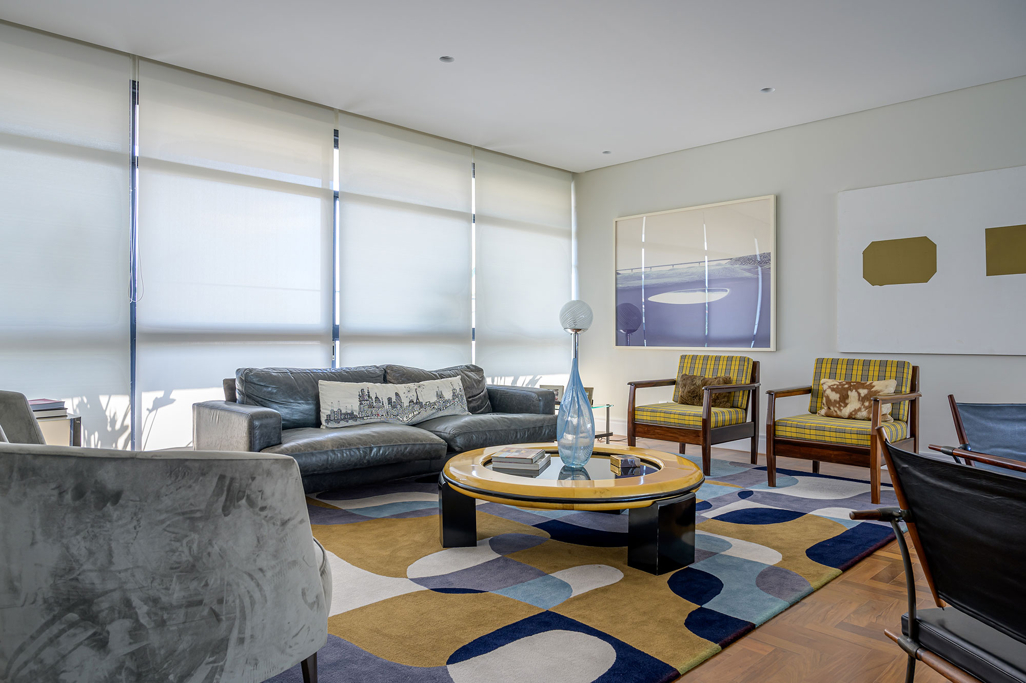 Apartamento de 380 m² é morada e galeria de arte ao mesmo tempo. Projeto de Pedro Coimbra. Na foto, sala com quadros, tapete e sofá.