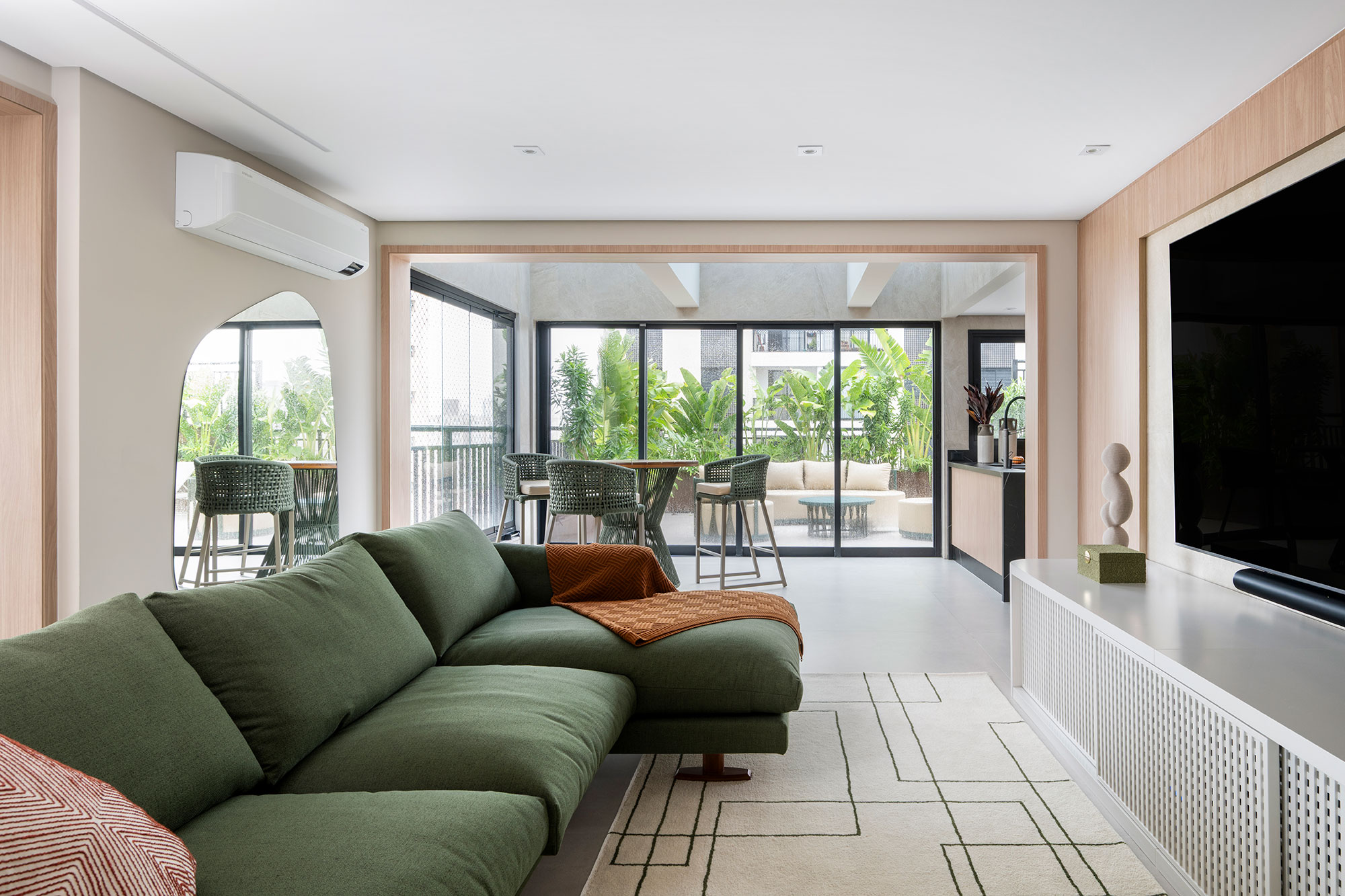 Duplex ganha cara de casa com área externa repleta de verde. Projeto de Erica Salguero. Na foto, sala de Tv, gourmet e varanda.