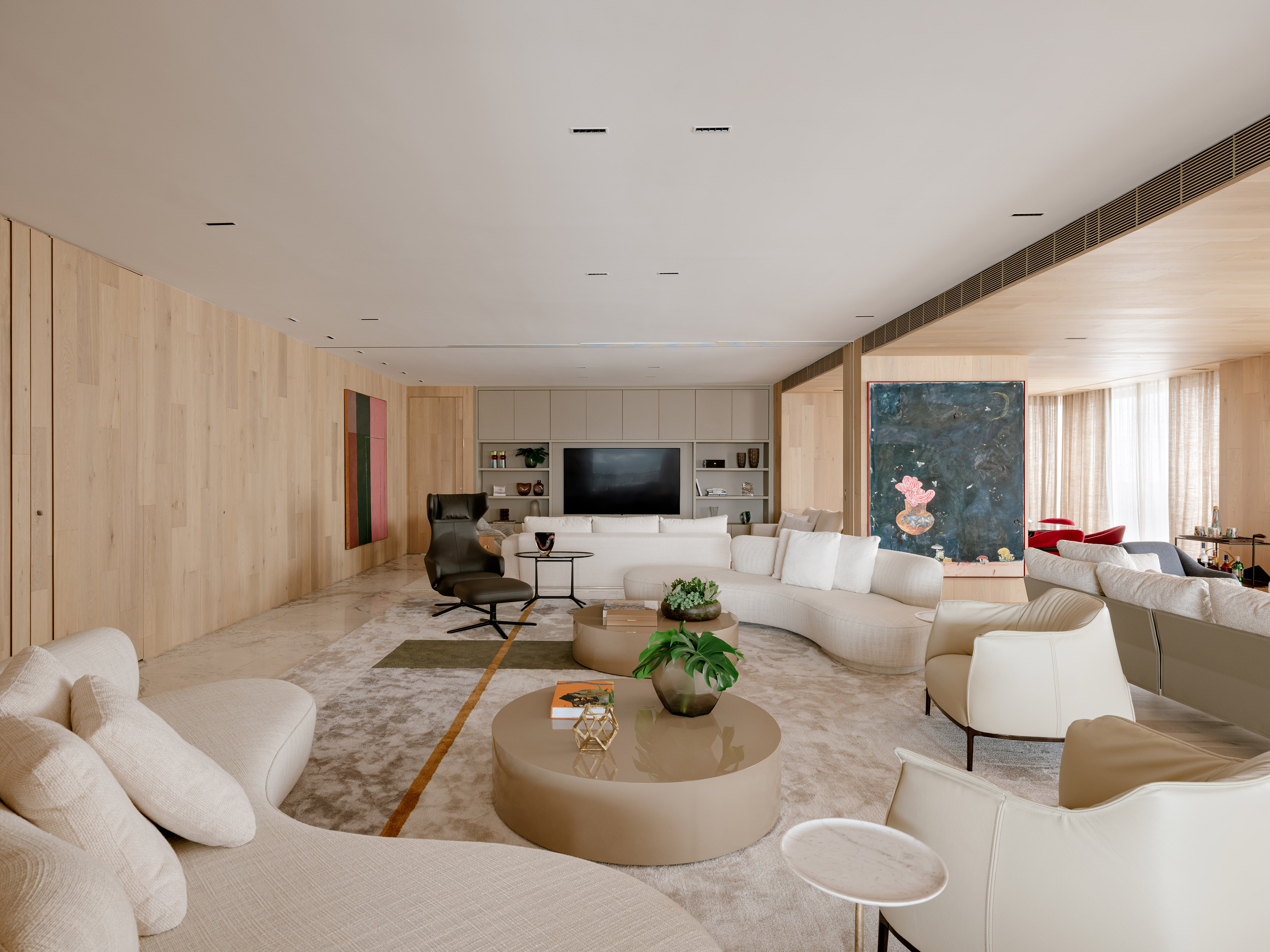 Apartamento de 470 m² prioriza materiais naturais em um décor atemporal. Projeto de David Bastos. Na foto, sala integrada com a varanda e sofás curvos.