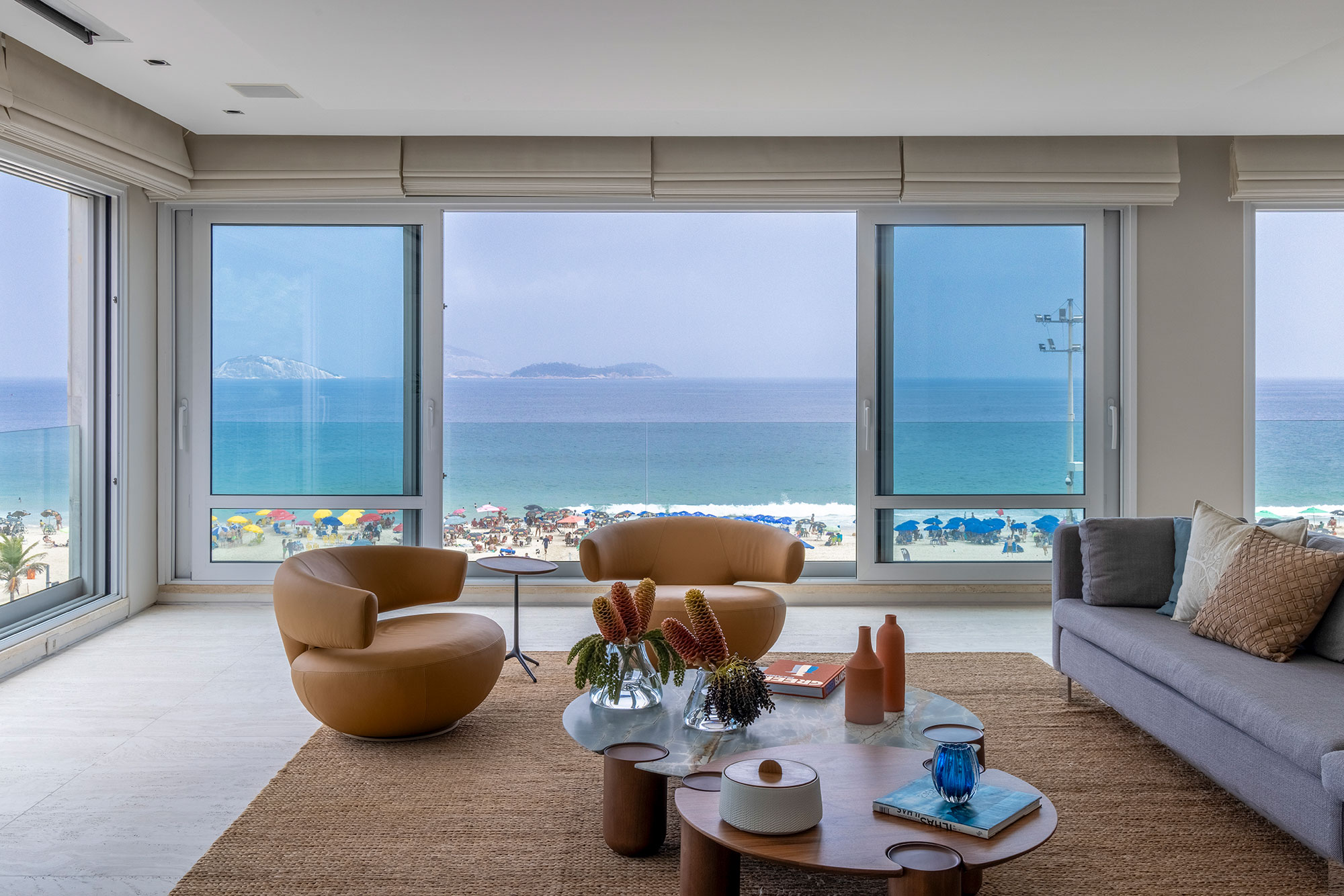 Cores de Ipanema inspiram décor deste apartamento com amplas janelas. Projeto de Andrea Chicharo. Na foto, sala com vista para o mar e sofá cinza.