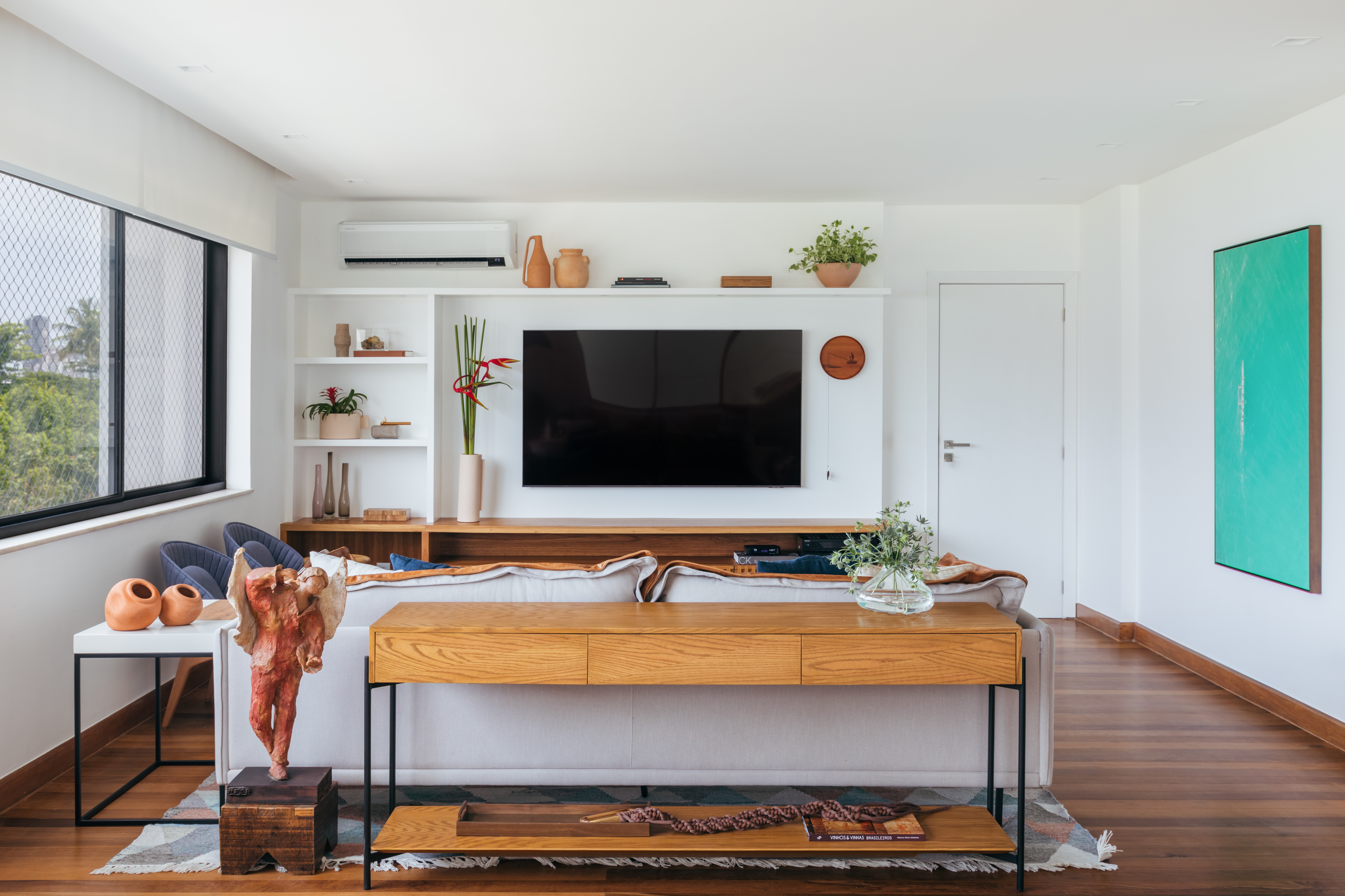 Design assinado e marcenaria exclusiva são destaques neste apê de 250 m². Projeto de Fernanda Medeiros. Na foto, sala de estar com tv e sofá branco.