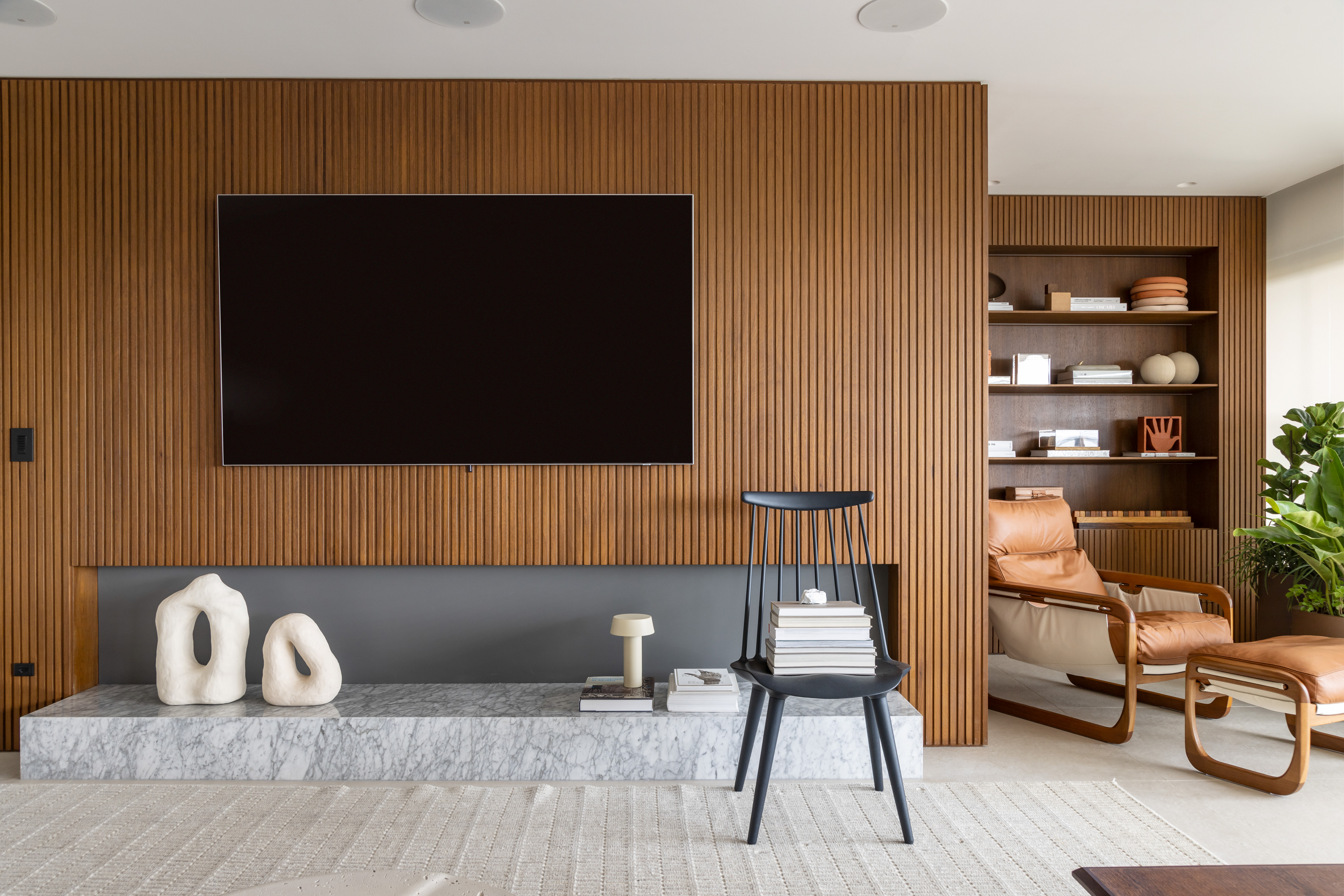 Peças assinadas e layout fluido marcam apê de 230 m². Projeto de Sala2 Arquitetura. Na foto, sala de TV com parede ripada.
